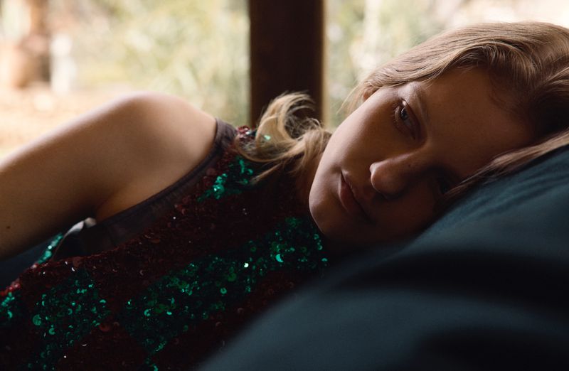Close-up portrait of a woman resting on a dark pillow wearing a sequined top for Vogue Thailand