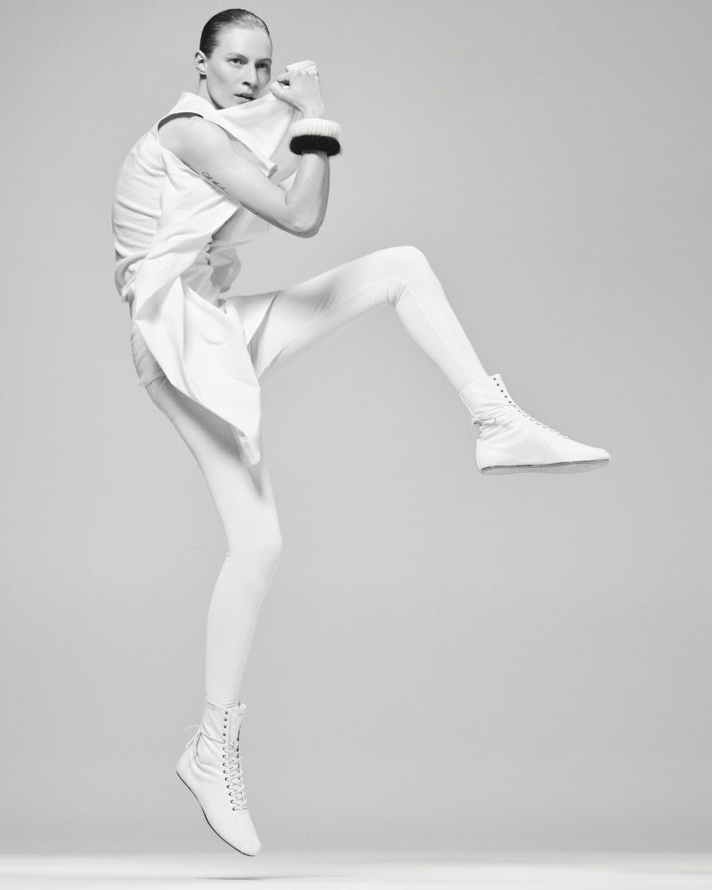 Model Julia Nobis jumping in white clothing against a seamless grey background for Mastermind Magazine.