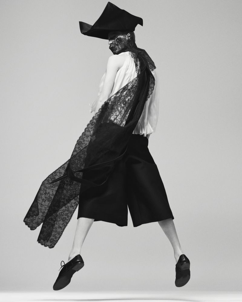 Model Julia Nobis jumping in avant-garde black hat and lace sash for Mastermind Magazine by Ethan James Green