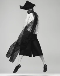 Model Julia Nobis jumping in avant-garde black hat and lace sash for Mastermind Magazine by Ethan James Green