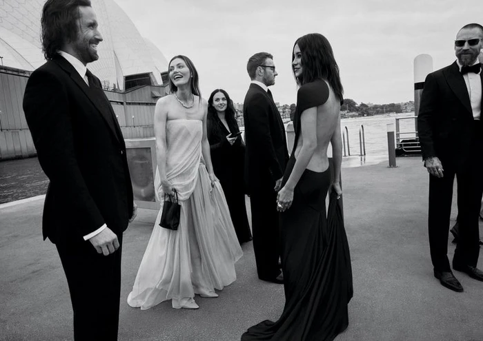 Monochrome editorial photo of formal guests gathered on a pier with the Sydney Opera House visible in the background.