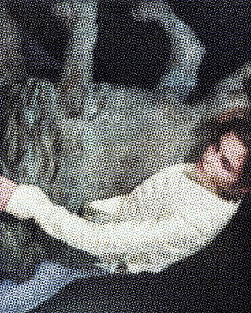 Model lying against a textured sculptural grey form in an editorial photograph for Pop Magazine