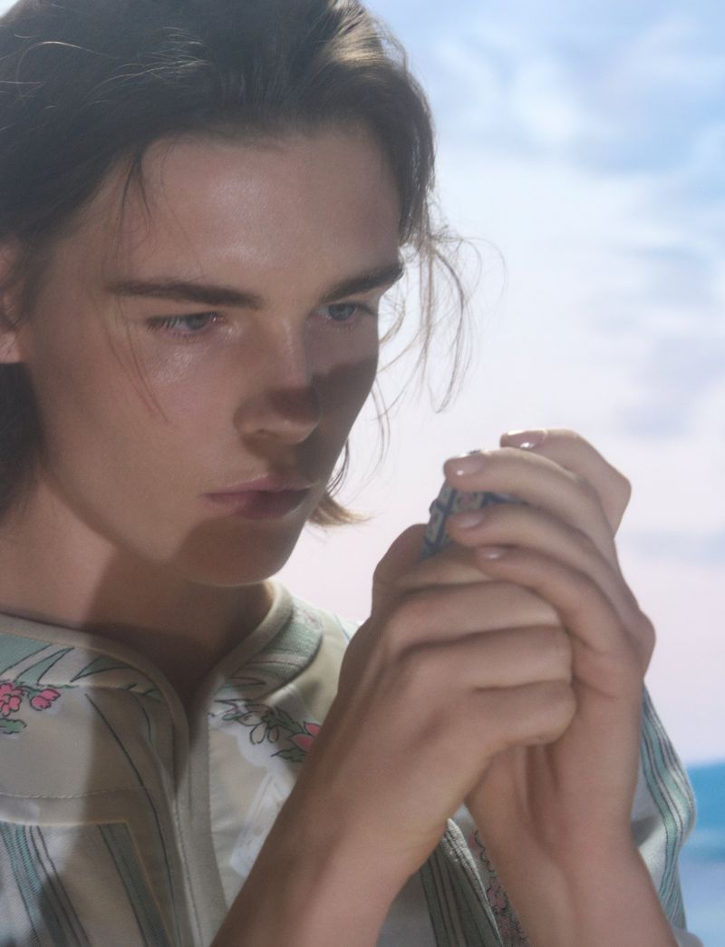 Close-up portrait of a model holding a small object outdoors under natural sunlight for Pop Magazine