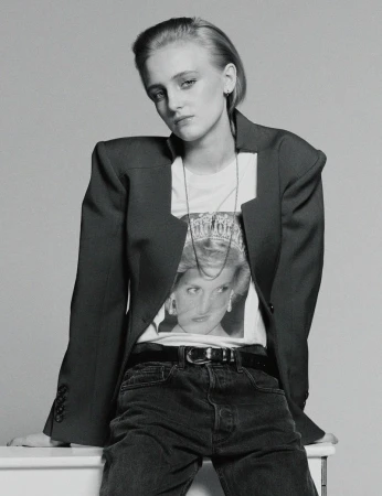Monochrome portrait of a model in a dark structured blazer and graphic t-shirt against a grey background