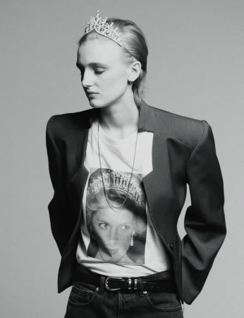 Monochrome portrait of a model wearing a tiara and graphic t-shirt under a structured blazer against a grey backdrop