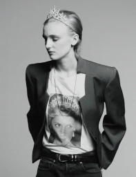 Monochrome portrait of a model wearing a tiara and graphic t-shirt under a structured blazer against a grey backdrop