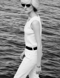 Model in white tank top and trousers wearing sunglasses standing by rippling water in Pop Magazine editorial
