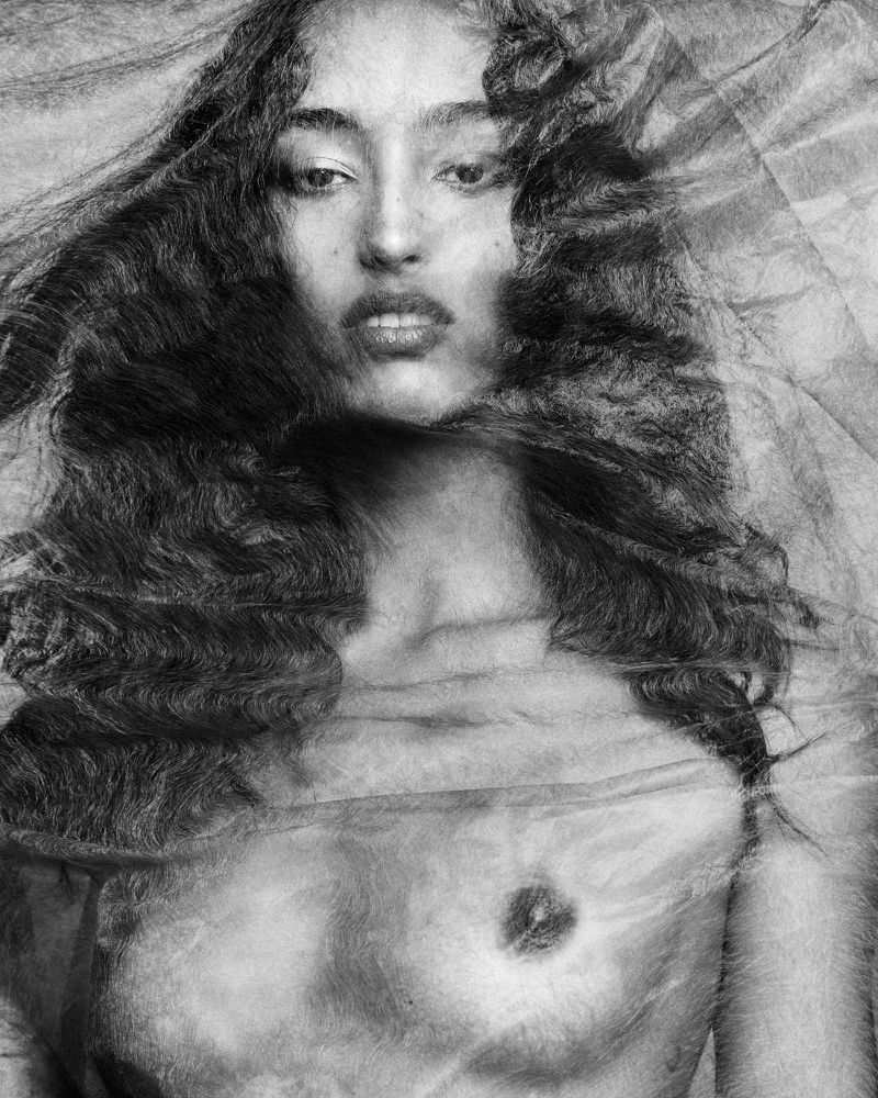 Mona Tougaard behind sheer textured fabric in a monochrome portrait by Luigi and Iango.