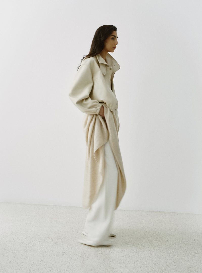 Model Nora Attal standing in a long cream-coloured coat for the Nour Hammour Spring Summer 26 collection campaign.