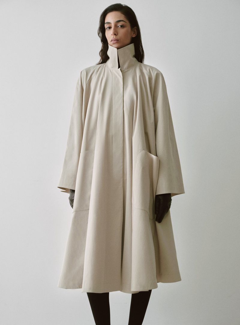 Model Nora Attal in a high-necked cream coat for Nour Hammour Spring Summer 26 against a white background