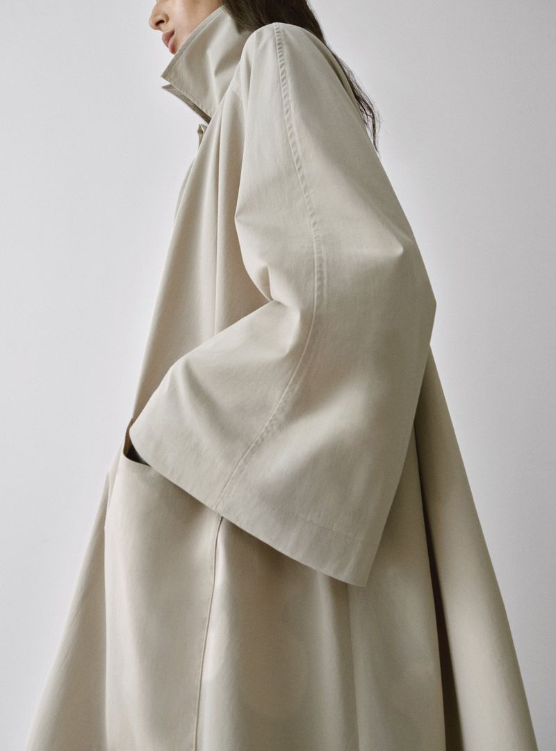 Model Nora Attal wearing an oversized cream trench coat against a white background for Nour Hammour Spring Summer 26.