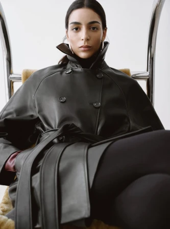 Model Nora Attal seated wearing a black leather coat and turtleneck for Nour Hammour Spring Summer 26.