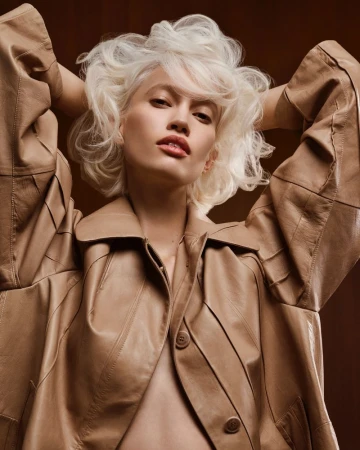 Model with voluminous blonde hair wearing a beige leather jacket, photographed by Karel Losenicky for Grazia Italy.