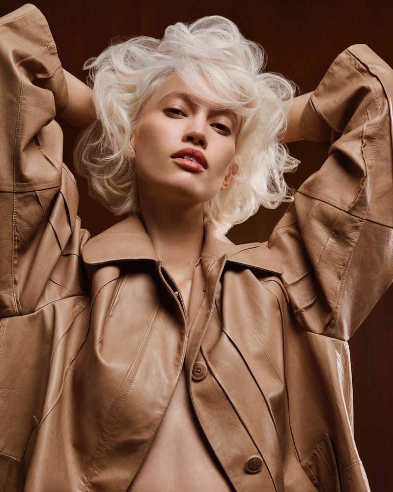 Model with voluminous blonde hair wearing a beige leather jacket, photographed by Karel Losenicky for Grazia Italy.
