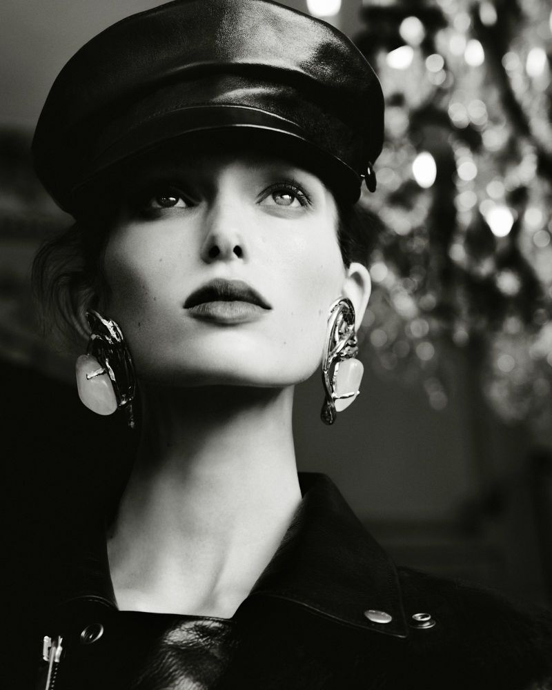 Close-up portrait of a woman wearing a leather cap and statement earrings, shot in monochrome for Beyond Noise.