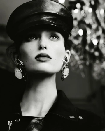 Close-up portrait of a woman wearing a leather cap and statement earrings, shot in monochrome for Beyond Noise.