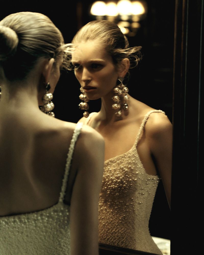 Model wearing pearl-encrusted dress and large ball drop earrings looking into mirror for Beyond Noise Issue 5