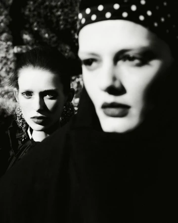 Two women posing in a high contrast black and white fashion portrait with one wearing a polka dot headscarf