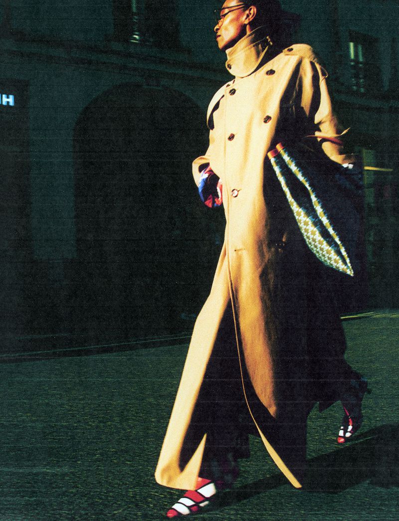 Model in a long tan trench coat walking outdoors at night on a dark street for The Face Magazine editorial Women of Frequency