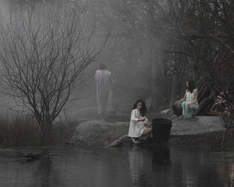 Three figures in muted attire near a misty wooded riverbank for the I'TIMAD project by Dazed MENA, photographed by Billel Ouazene.