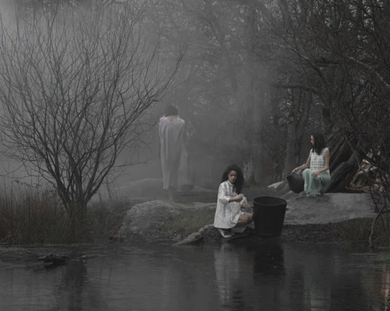 Three figures in muted attire near a misty wooded riverbank for the I'TIMAD project by Dazed MENA, photographed by Billel Ouazene.