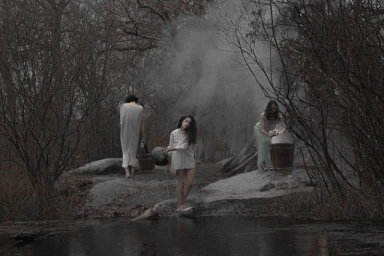 Three figures in a misty wooded landscape near water, with one pouring water from a bucket into a stream.
