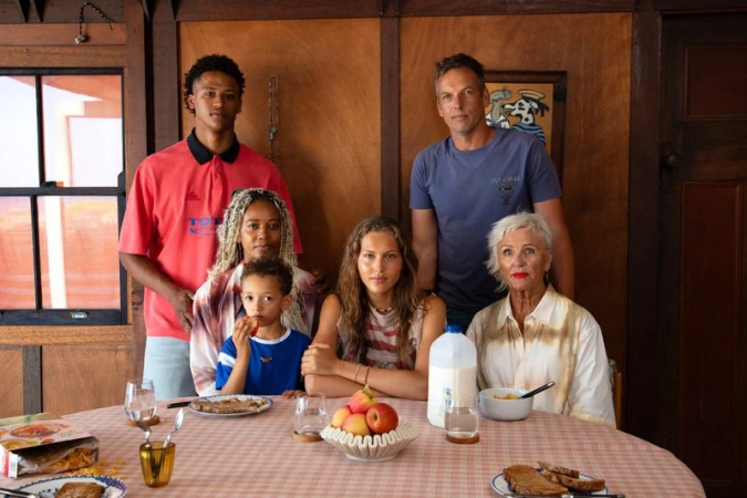 Group portrait of six diverse people seated and standing around a table inside a wood-paneled room for Pop Magazine