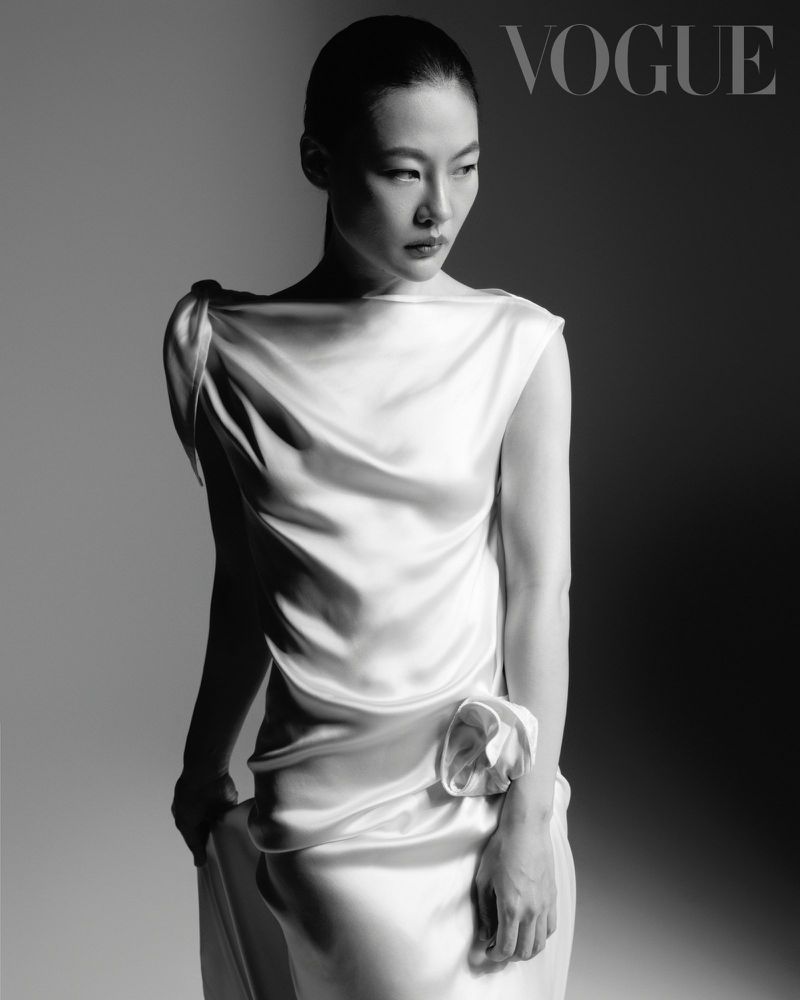 Monochrome portrait of Zine Tseng wearing a sleeveless white satin dress with a draped neckline for Vogue Taiwan.