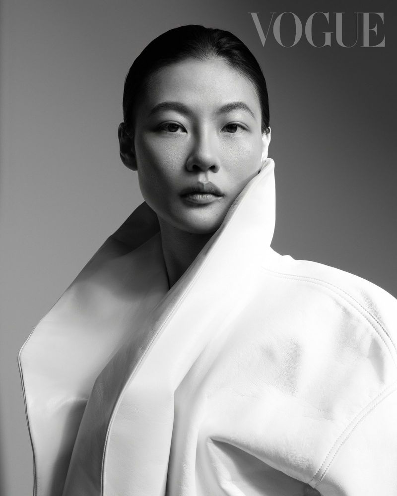 Portrait of a woman wearing a high-collared white coat against a seamless grey backdrop for Vogue Taiwan.