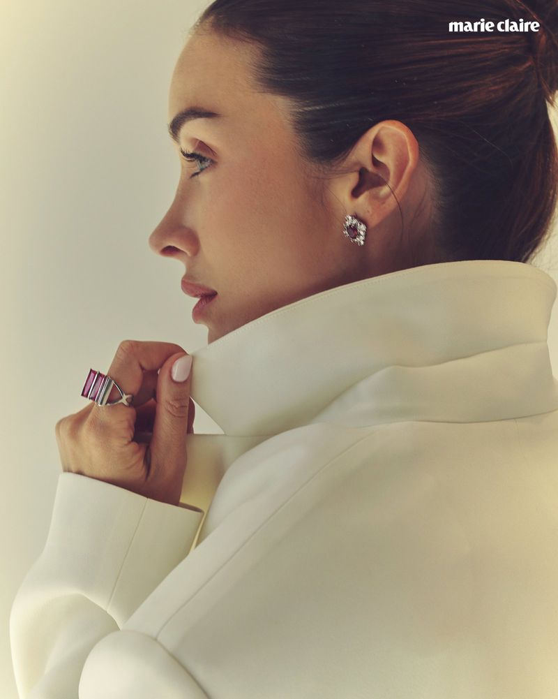 Profile portrait of a woman wearing a white high-collar coat, gemstone ring, and diamond earrings for Marie Claire Mexico.