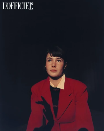 Model Grace Burns wearing a red blazer and black top against a dark background in an editorial portrait for L'Officiel USA.