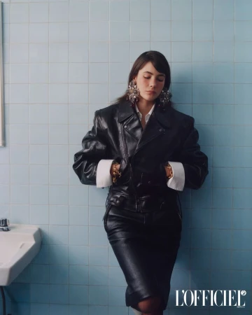 Model Grace Burns wearing a black leather jacket against a blue tiled wall for L'Officiel USA