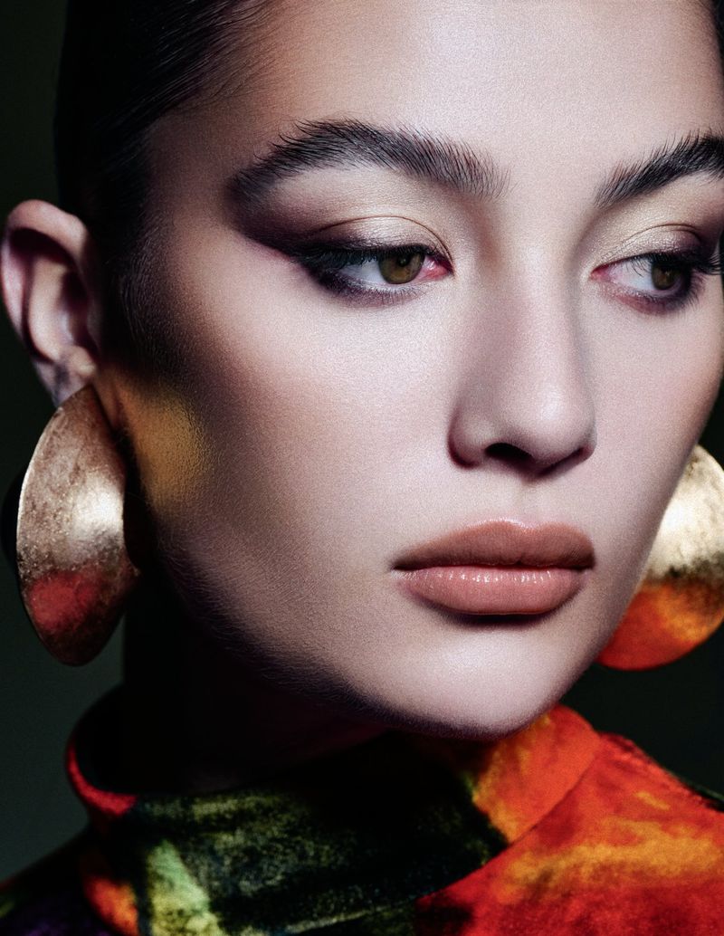 Close-up portrait of a woman wearing large gold earrings and a patterned top for Schon Switzerland