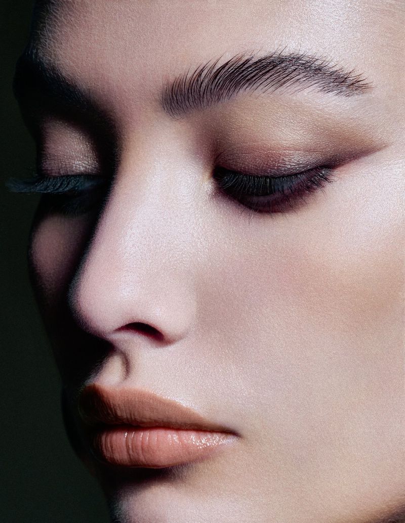 Close-up beauty portrait of a woman with dramatic eye makeup and feathered eyebrows for L entre Deux by Schön Switzerland.