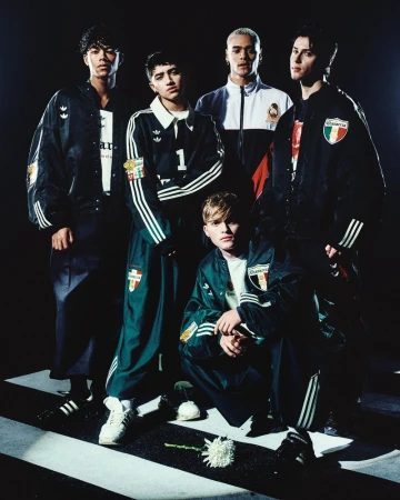 Group of five models wearing athletic tracksuits and jackets in a studio setting by Willy Chavarria