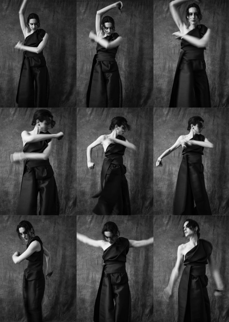 Monochrome multi-frame sequence of a model dancing in a black one-shoulder top and trousers against a textured backdrop.