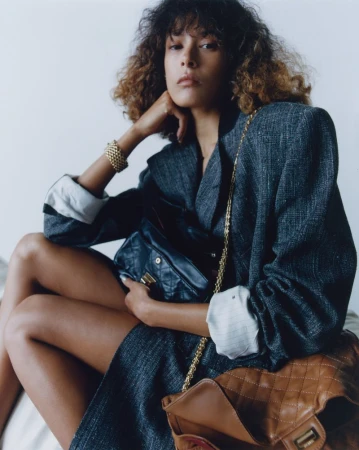 Model Prinnie Stott wearing a charcoal blazer holding a black quilted handbag for Puss Puss Magazine