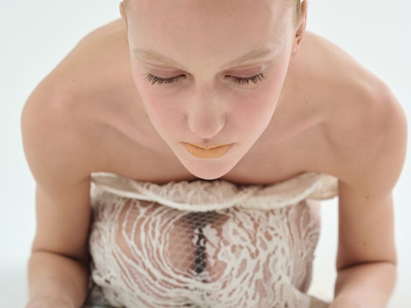 High-angle portrait of a woman wearing an ivory lace strapless dress against a white background for Vogue Czechoslovakia