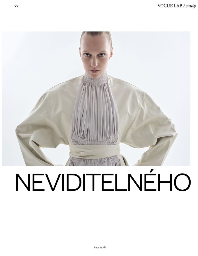 Model wearing a structured cream dress with pleated center panel against a plain white background