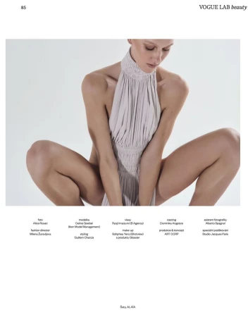 Model wearing a pleated halterneck dress crouching against a plain white studio background for Vogue Czechoslovakia