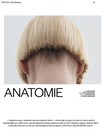 Close-up back view of a person with blonde bowl-cut hair against a pale grey studio background
