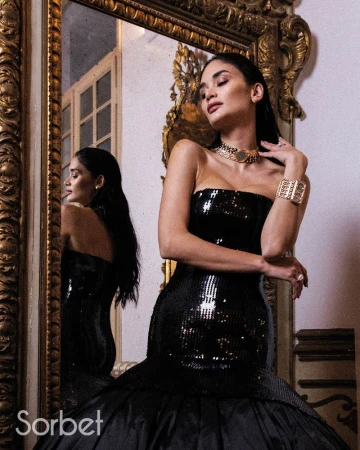 Woman in a black sequin dress posing in front of an ornate golden mirror for Sorbet Magazine