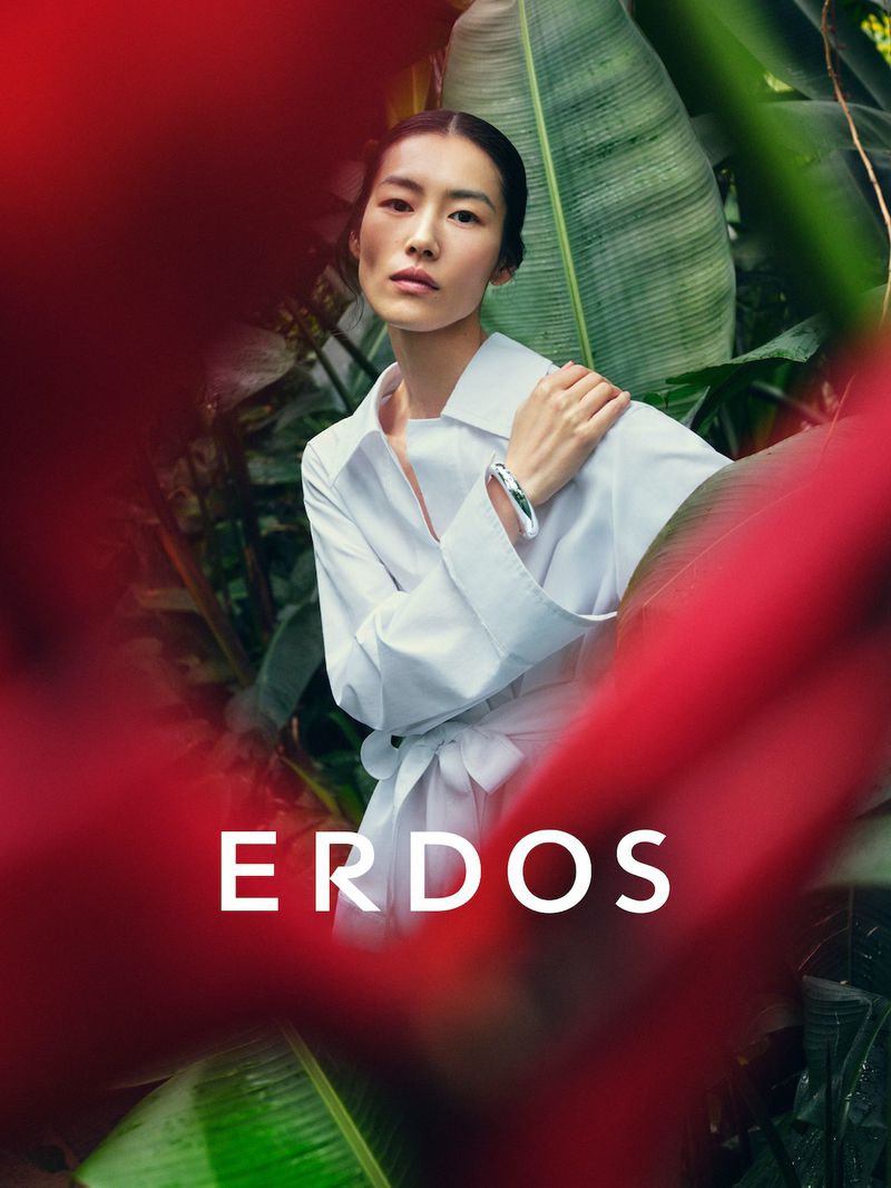 Model Liu Wen wearing a white shirt amid lush tropical foliage with blurred red foreground framing