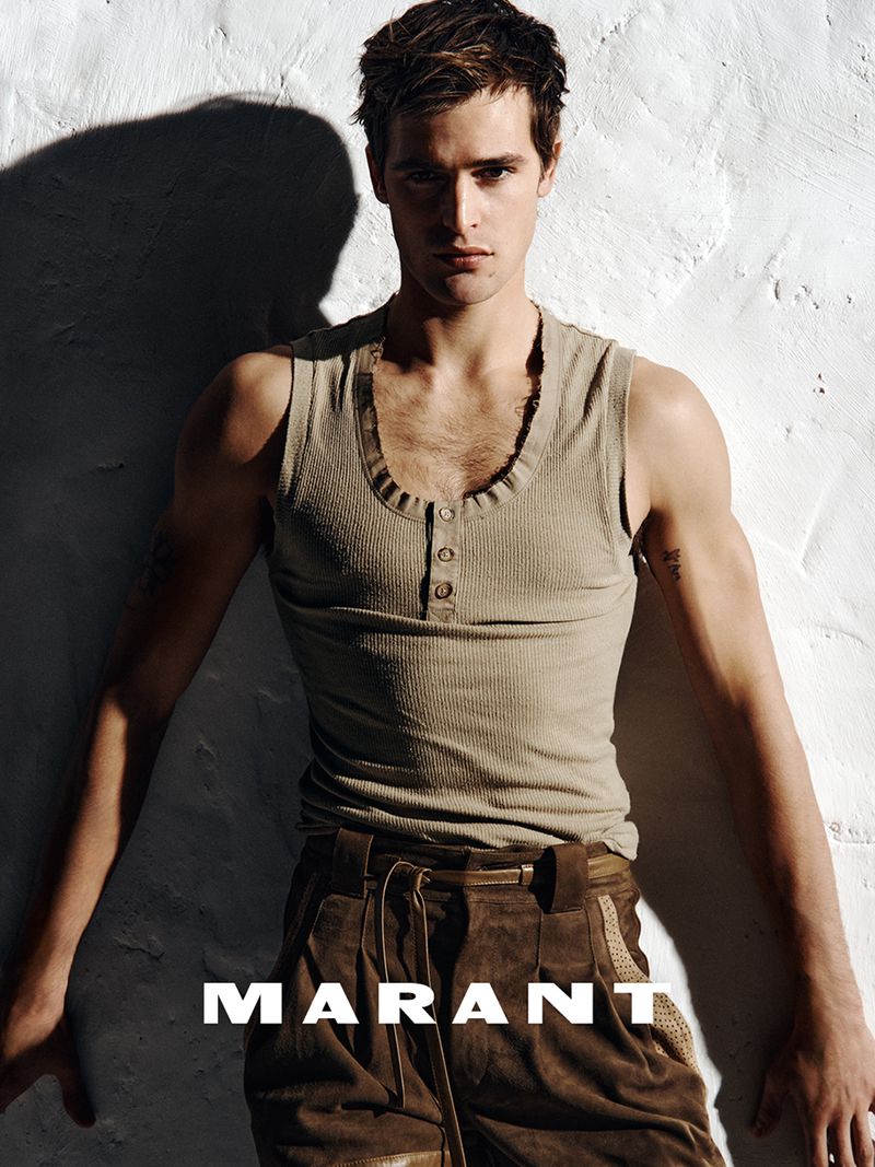 Parker Van Noord wearing a beige ribbed tank top and brown trousers against a white textured wall for Isabel Marant