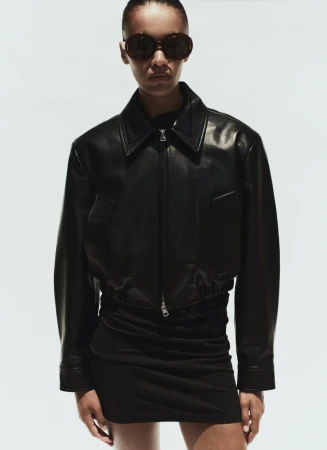 Model wearing a black leather jacket and sunglasses against a seamless white background for AGOLDE Spring 2026.