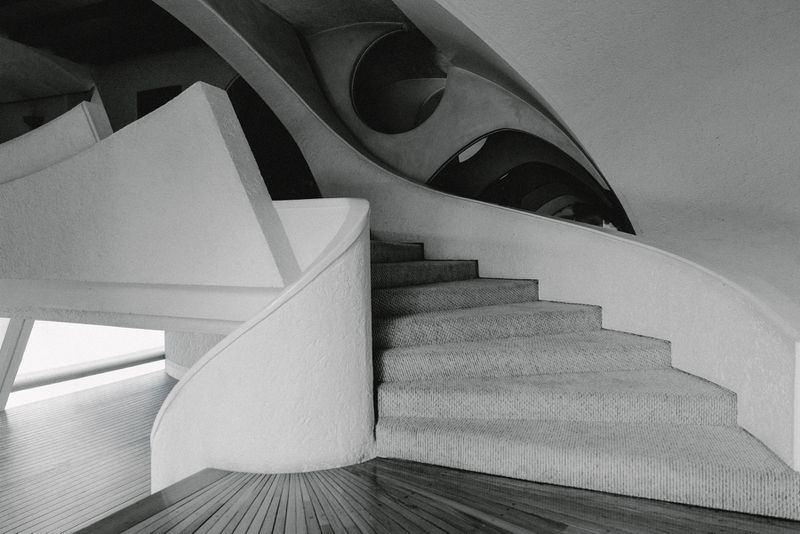 Monochrome interior view of modern architectural concrete staircase with curved handrail and angular ceiling structure