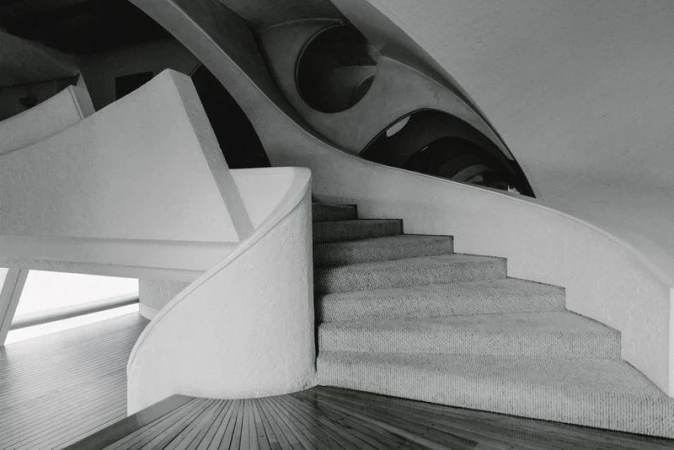 Monochrome interior view of modern architectural concrete staircase with curved handrail and angular ceiling structure
