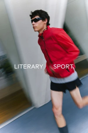 A male model wearing a red athletic jacket and dark sunglasses running outdoors with motion blur in an SS 2026 campaign.