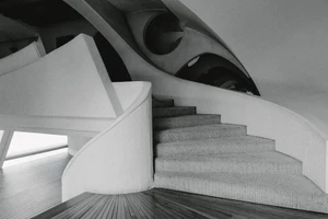 Monochrome interior view of modern architectural concrete staircase with curved handrail and angular ceiling structure