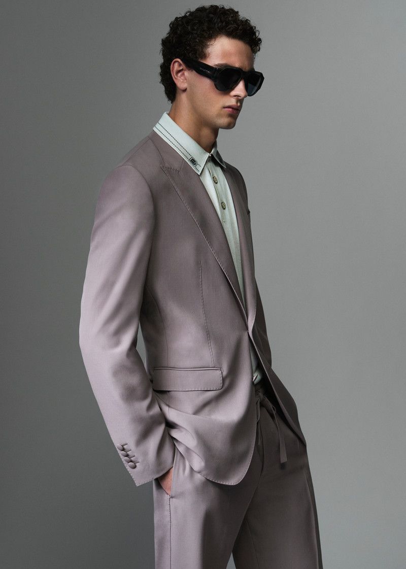 Model wearing a tailored taupe suit jacket and sunglasses against a grey backdrop for Dolce & Gabbana Mens S/S 26